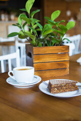 Coffee mug on wooden table, sweet wafer on a plate. Close-up.