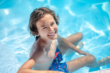 Boy sitting in the water in the pool