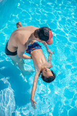 Standing man and lying back boy in water