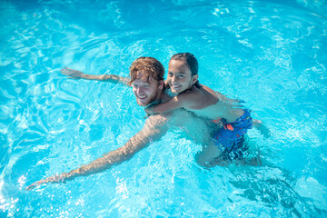 Dad with son on his back swimming in pool