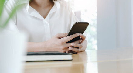 Closeup image of a beautiful Asian woman holding , using and looking at smart phone.