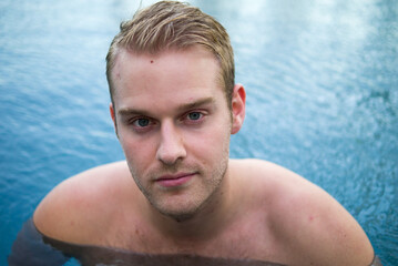 Young handsome shirtless man with blond hair in the swimming pool