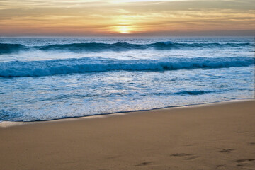 Foamy beach waves with amazing sunset. Endless horizon. Stunning colors