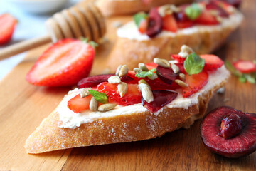 Sandwich with strawberries, cherries, soft cheese and sunflower seeds served with honey. Top view with copy space.