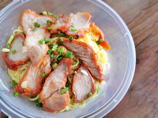 BBQ pork with egg noodles on a plastic bowl   Selective focus.