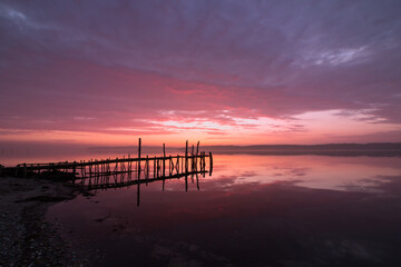 brilliant seascape sunset with jetty and glowing red sky at dawn 