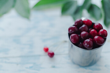 Cherries in a steel mug on a wooden background