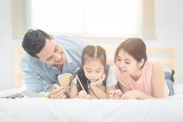 Happy family in the bedroom,Asian father and mother teaching her daughter child to studying at home.Photo series of family, kids and happy people concept.
