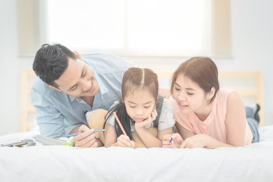 Happy family in the bedroom,Asian father and mother teaching her daughter child to studying at home.Photo series of family, kids and happy people concept.