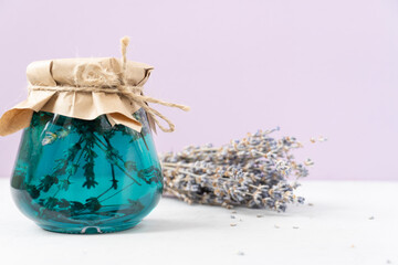 Jar  of lavender jam wrapped in brown paper on a light lilac background. copy space.