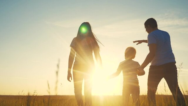 happy family and kid together fun walk at sunset in the park in nature. mom dad and boy son walk outdoor in the park sunset silhouette. parents and child together are walking. people lifestyle in the