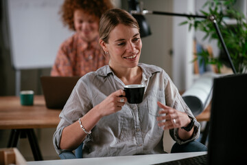  Young businesswoman drinking coffee in her office. Beautiful businesswoman enjoying in the mornings.