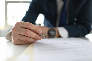 Man's hands in a business suit makes notes at the table. Businessman busy with professional career...