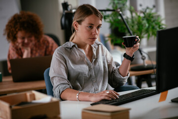  Young businesswoman drinking coffee in her office. Beautiful businesswoman enjoying in the mornings.