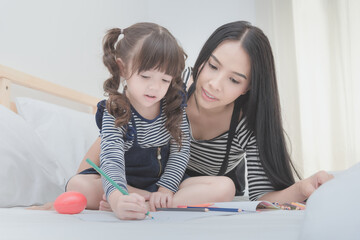 Happy family in the bedroom,Asian mother teaching her daughter child to learning for  preschool. Photo design for family, children and happy people concept.