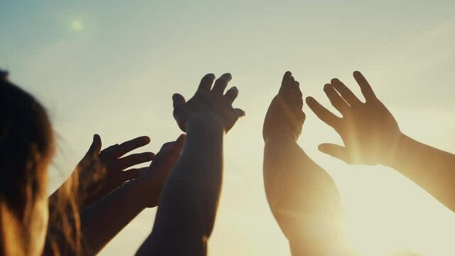 happy family people group pull hands to the sun teamwork. silhouette people party dancing recreation holiday. people at a music concert pull their hands up. religion concept sunlight lifestyle