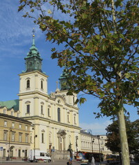 Fototapeta na wymiar Warsaw, Poland: Copernicus Square on a background of green tree and a building with a cathedral with crosses in the early morning