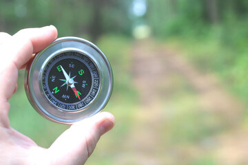 Old classic navigation compass in hand on natural background as symbol of tourism with compass,...