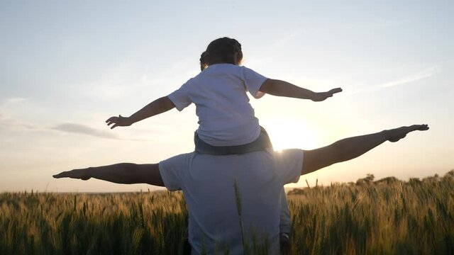 happy family silhouette teamwork concept slow motion video. daughter little girl sitting on his father man neck depicts a flight of an airplane playing a pilot. parent dad and child kid lifestyle