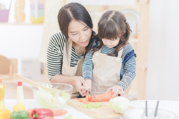 Happy loving family of asian mother and her daughter prepare healthy food salad in kitchen room.