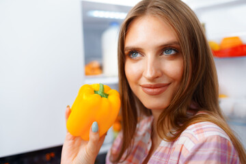 Portrait of a young blonde woman taking food from her fridge