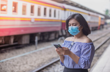 young woman wearing medical mask using a mobile phone