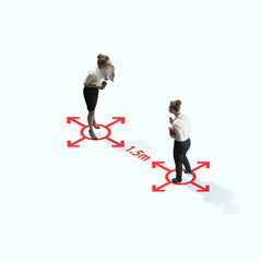Studio shot of people demonstrating social distancing with arrows indicating the separation. Office workers during coronavirus outbreak with new rules for safety and healthcare. High angle view