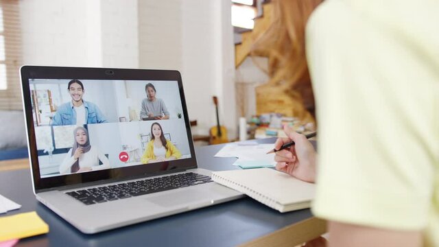 Asia businesswoman using laptop talk to colleagues about plan in video call meeting while working from home at living room. Self-isolation, social distancing, quarantine for corona virus prevention.