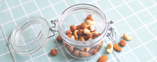 Mix of nuts in a glass jar. Cashews, hazelnuts and almonds. Selective focus, copy space. The concept of vegetarian and organic food.