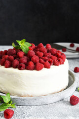 Cake with cream cheese and raspberries and mint on the kitchen table. Birthday cake.