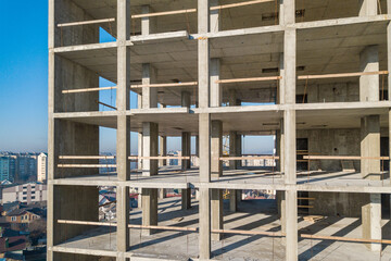 Aerial view of concrete frame of tall apartment building under construction in a city.