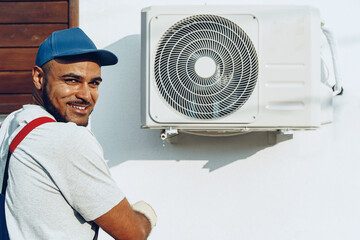 Repairman in uniform installing the outside unit of air conditioner