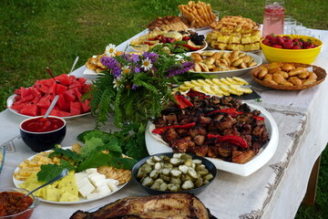 Traditional midsummer festive table with fried meat - shashlik, cheese, pies, fruit and other snacks, Latvia