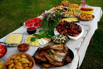 Traditional midsummer festive table with fried meat - shashlik, cheese, pies, fruit and other snacks, Latvia