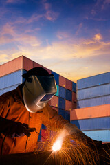 Industrial welding worker welding steel structure with cargo container stack in background for...