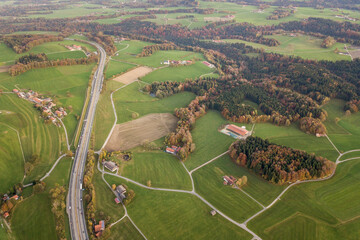 Aerial view of small scattered farm houses with red tiled roofs among green farming fields and...