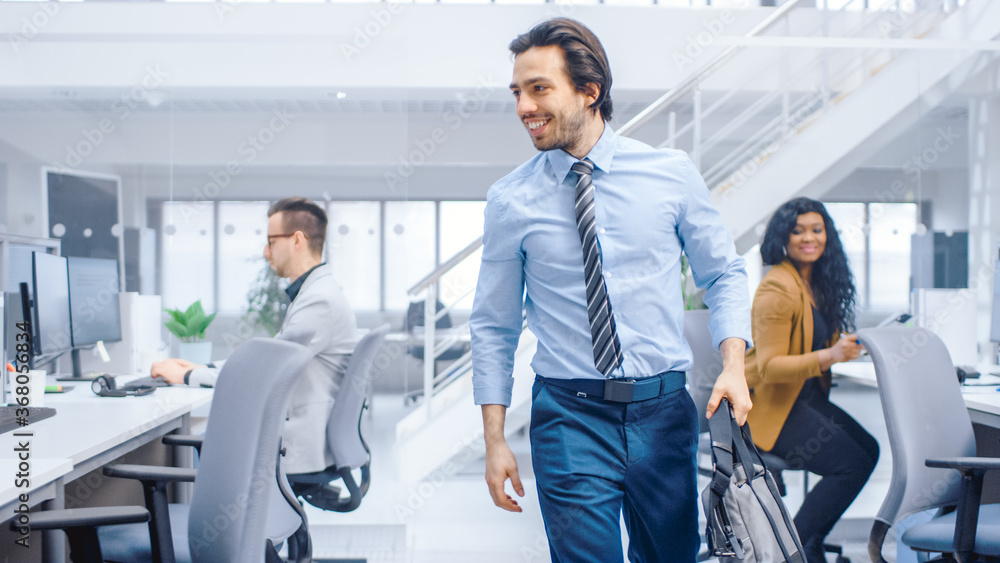 Wall mural young happy businessman returns to work after vacation, walks into bright modern office, greets ever