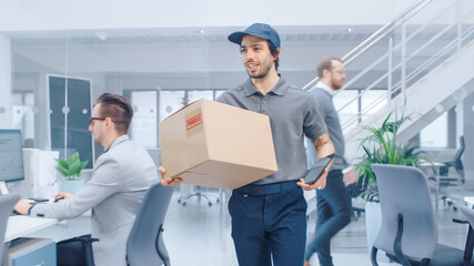 Happy Delivery Man Enters Corporate Office and Delivers Cardboard Package to a Worker. Big Bright Modern Business Company Office with Professional Businesspeople Working
