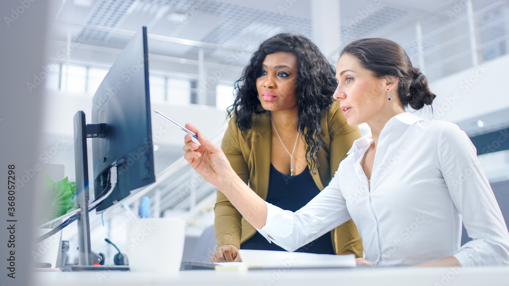 Poster in bright modern office: beautiful businesswoman sitting and working at her desktop computer with pr