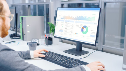 Over the Shoulder Shot of Motivated Businessman Working on Desktop Computer with Financial Data,...