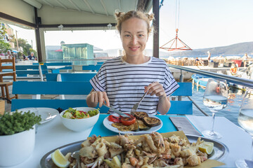 Beautiful female tourist eating delicious sea food on summer vacation in traditional croatian...