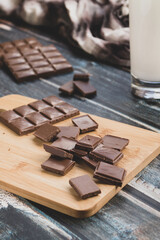 milk dark chocolate tiles on wood cutting board, wooden background