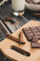 milk dark chocolate tiles on wood cutting board, wooden background