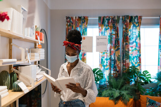 Black Woman Reading Book In Book Store During Quarantine Period