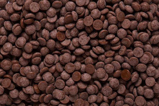 Dark chocolate chips for hot chocolate preparation or dessert ingredients. Cocoa chocolate morsels background