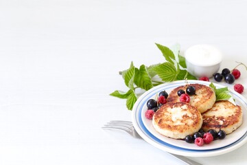 Cottage cheese pancakes with fresh berries, raspberries and black currants on a white background copy space 