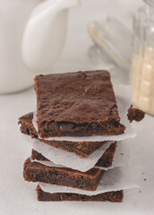 A stack of chocolate brownies with parchment paper between placed on white background. Delicious dessert.