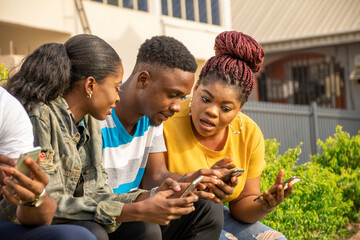 group of young black friends hanging out and using their mobile phones