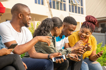 group of young african friends hanging out and using their mobile phones