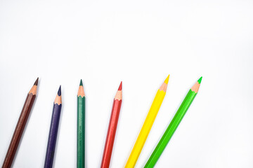 Seven different colored wood pencil crayons placed on a white background